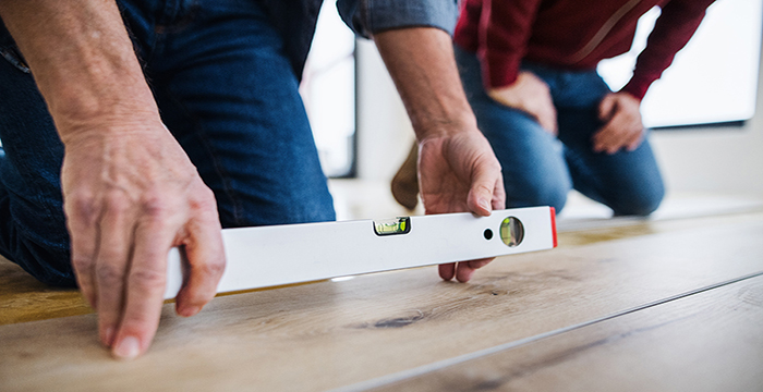 A midsection of man with his father laying vinyl flooring, a new home concept.
